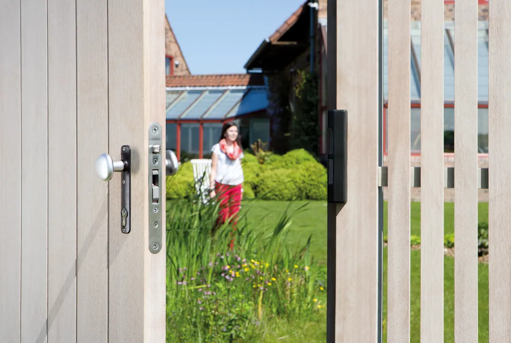 H-WOOD_3020-HYB-STD_SEH__Detail_wooden_gate_open_women_in_garden__1920px.webp