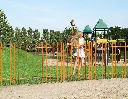 LAKZJ2_SMKL_3006WSI_SWING40__Girl_on_orange_fence_by_playground__1920px.webp