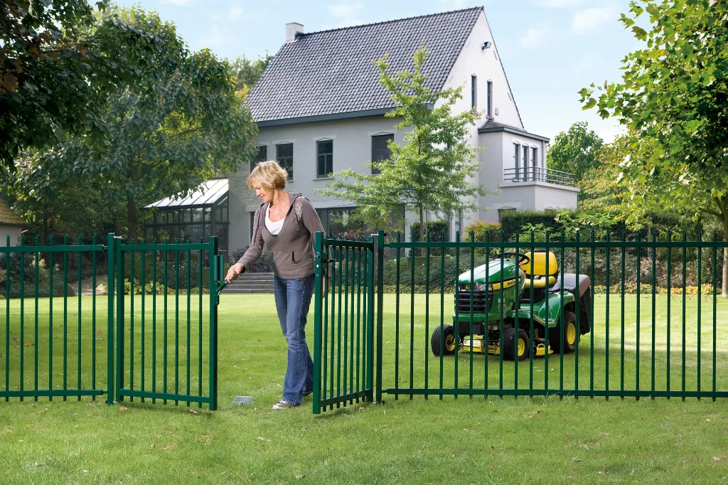 SUBY_LAKZP1_SMKL_GBM12_CGS__Woman_effortlessly_opening_green_garden_gate_lawnmower__1920px.webp